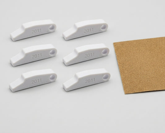 Six white 3D-printed 2011 blank sears with a sheet of sandpaper